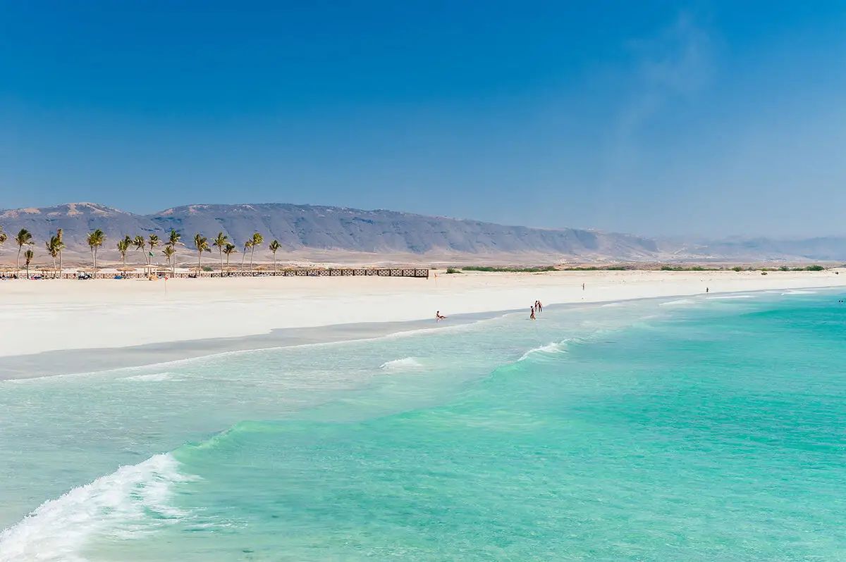Dlhá biela piesočná pláž v Salalahu s pohorím Dhofar